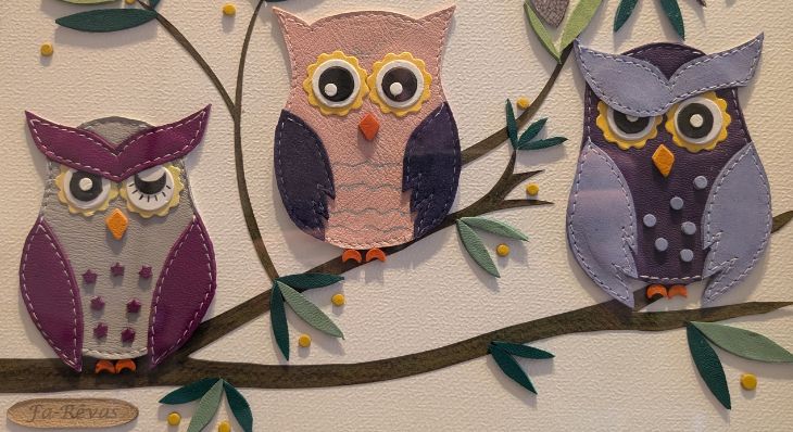 Porte carte en cuir représentant trois chouettes colorées posées sur une branche.