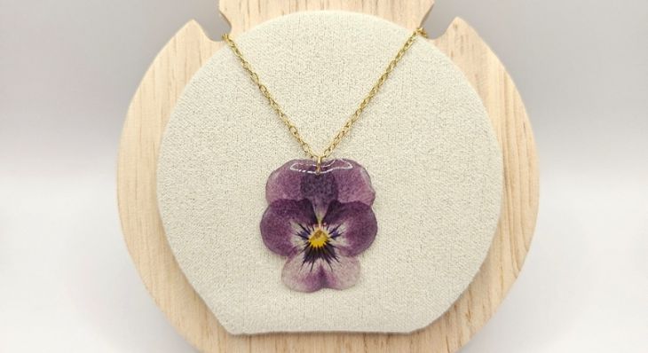 Collier artisanal L'Atelier d'Auriane avec pendentif en forme de véritable pensée violette séchée sur chaîne dorée.