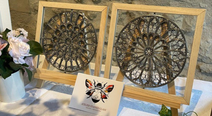 Deux vitraux circulaires style rosace encadrés de bois par l'Atelier Stained Glass, présentés avec une carte illustrée d'une abeille.