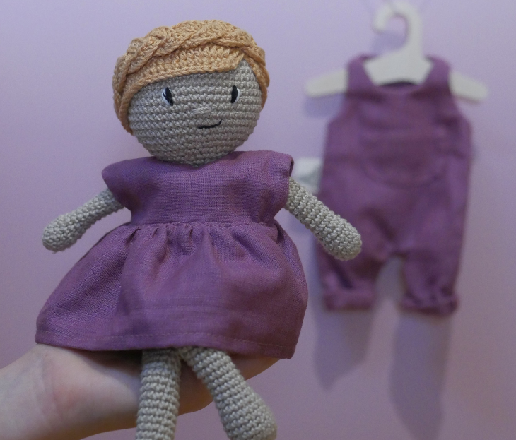 Poupée artisanale en crochet pour enfant avec cheveux blonds tressés et robe violette en tissu.