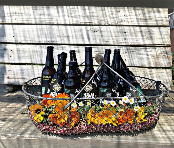 Bouteilles de bière artisanale dans un panier grillagé avec des fleurs