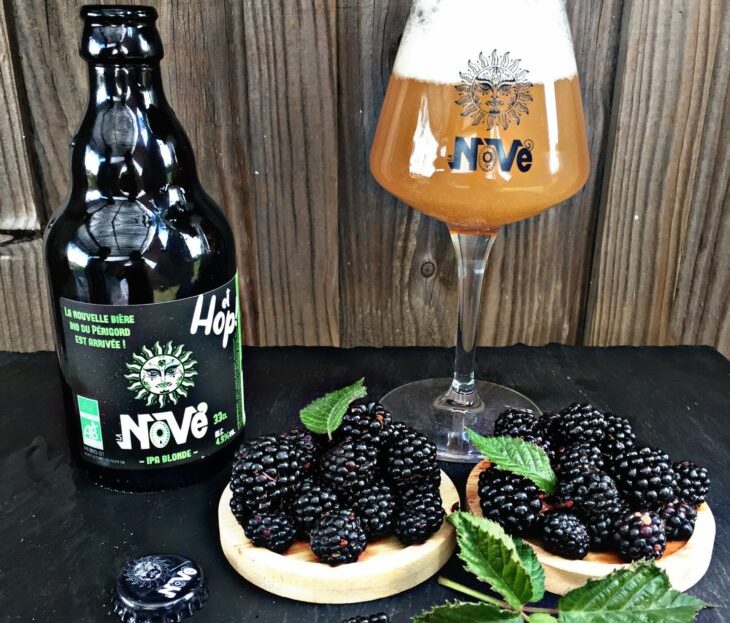 Bouteille de bière artisanale La Nove parfumée à la mûre avec un verre plein de bière et des mûres fraiches