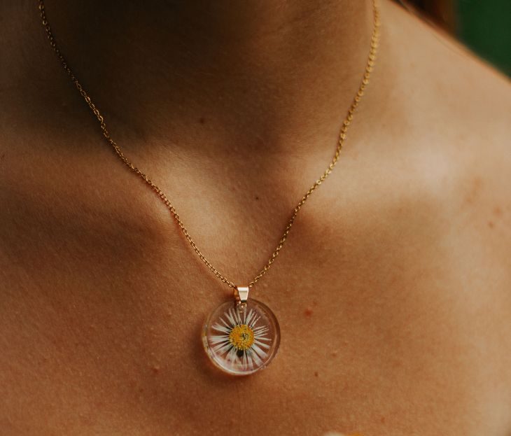 Femme portant un collier artisanal avec pendentif rond renfermant une véritable marguerite séchée par L'Atelier d'Auriane.