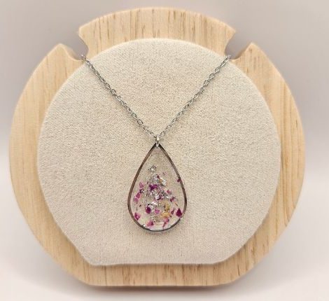 Pendentif artisanal L'Atelier d'Auriane en forme de goutte d'eau avec inclusions de pétales roses et éclats argentés.